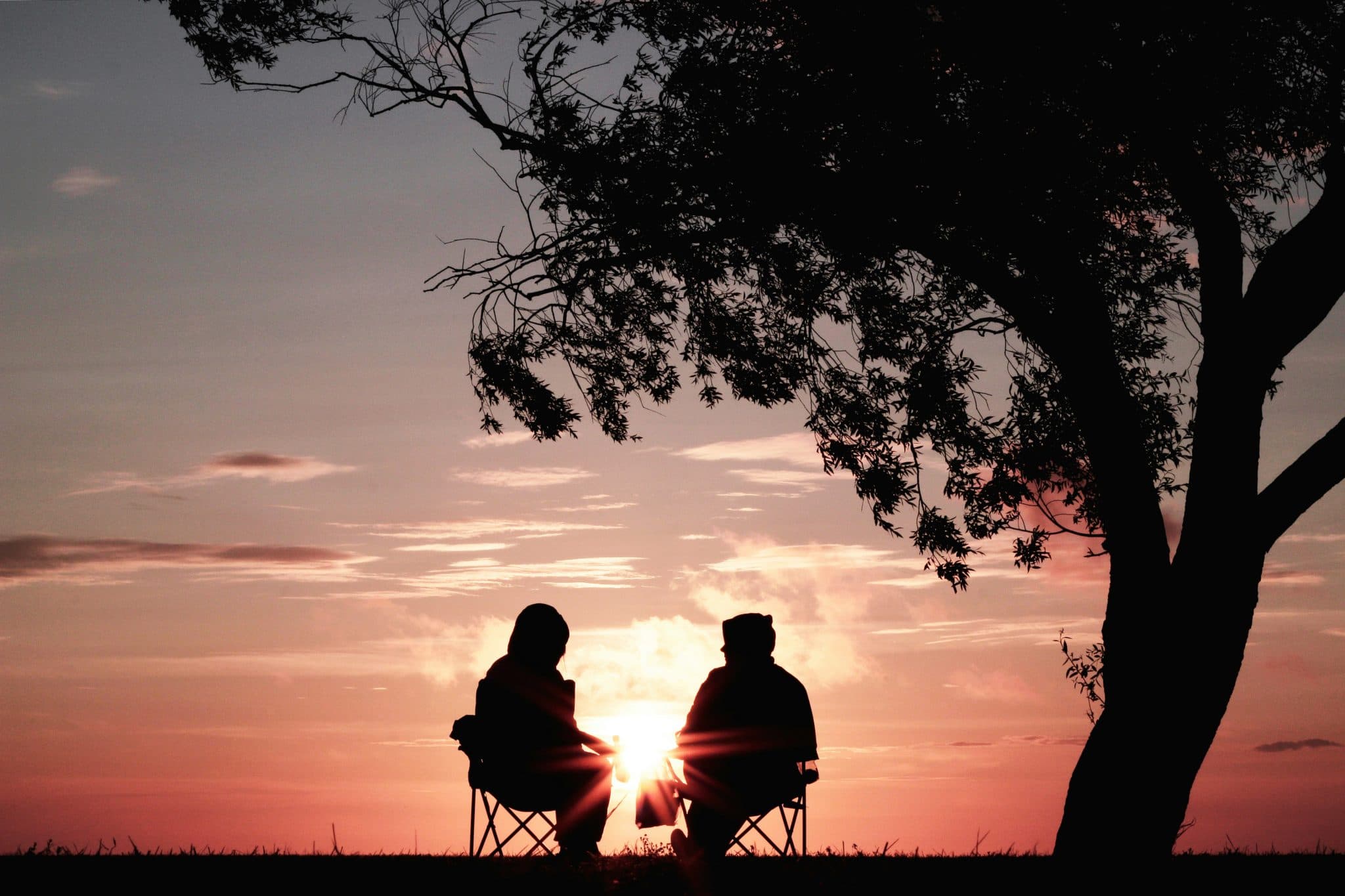 Two people sitting together watching a sunset — a metaphor for relationship.